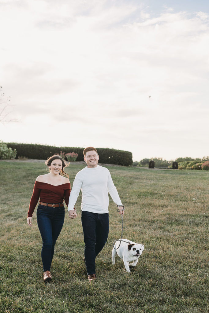 man and woman walk dog at their coxhall gardens engagement session