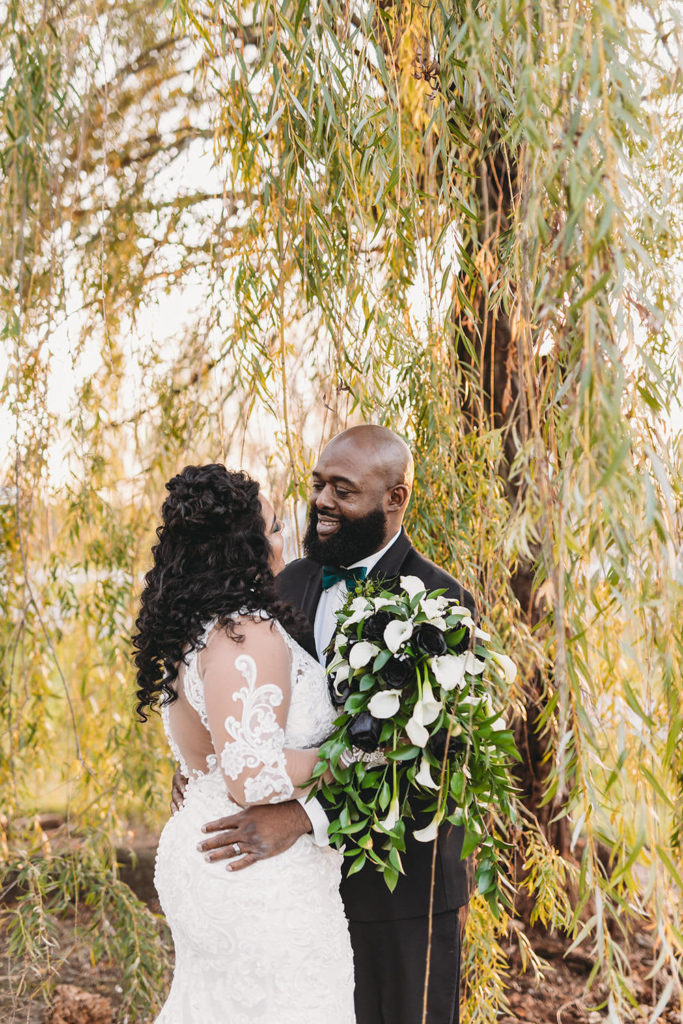 bride and groom amidst weeping willow tree branches before their ceruti wedding