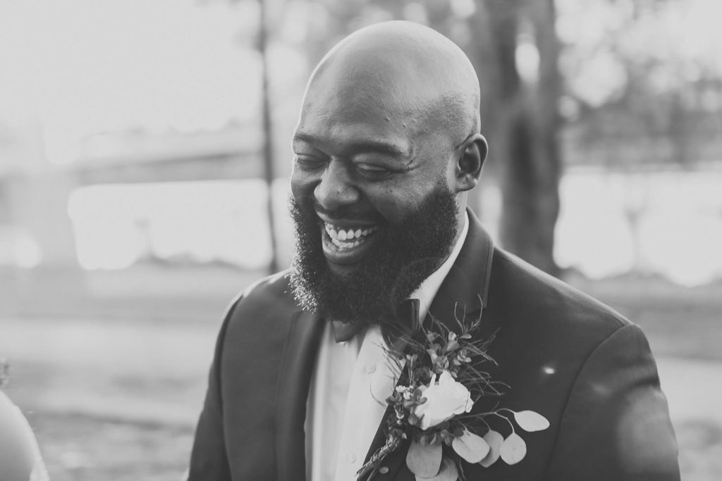 black and white image of groom laughing before his ceruti wedding