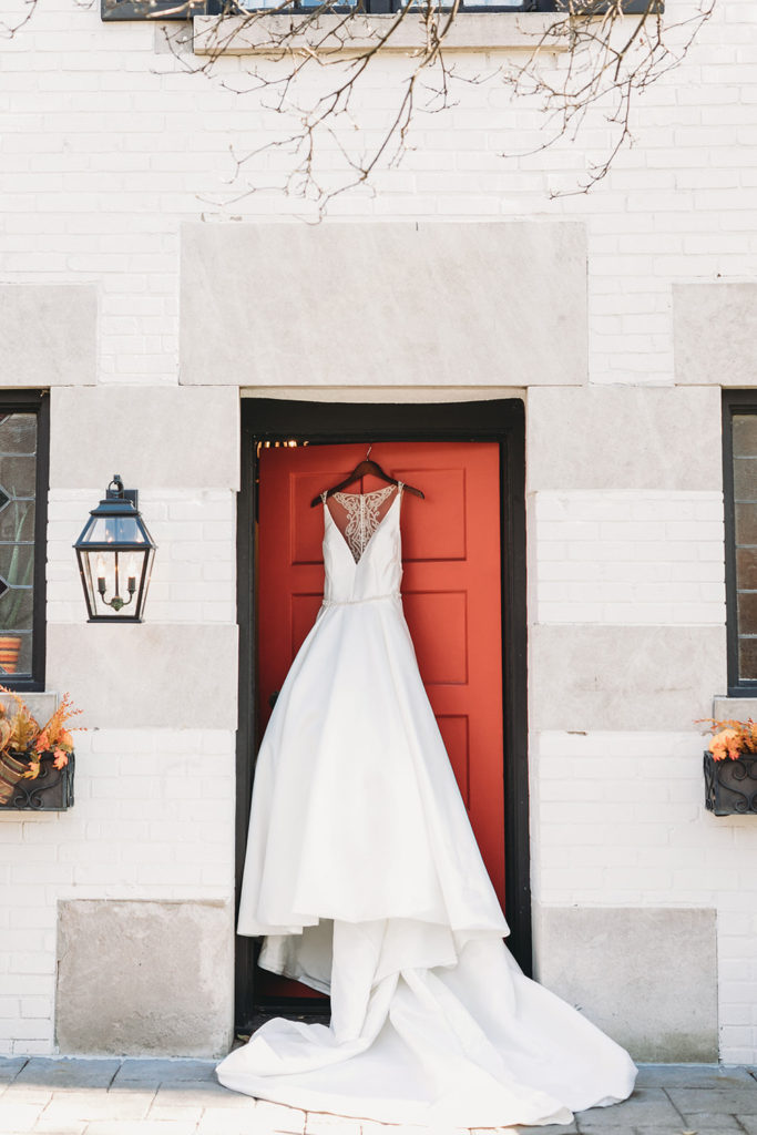 wedding dress on red door before bluffs wedding