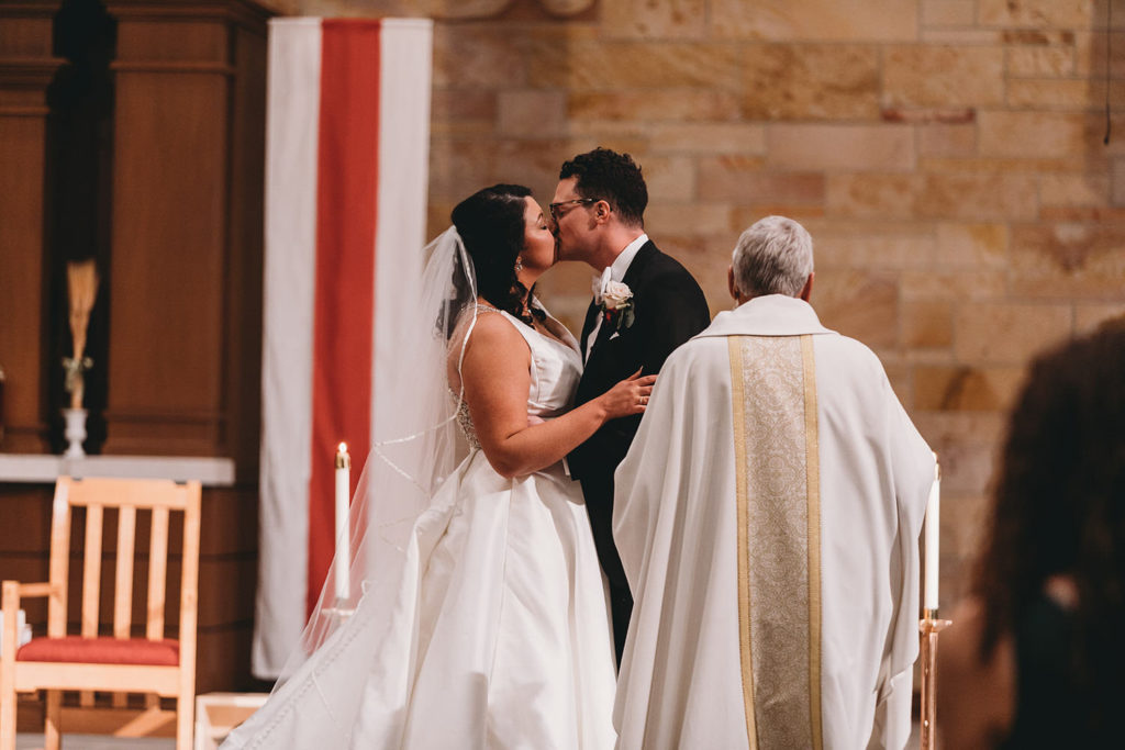 first kiss at immaculate heart of mary catholic church before bluffs wedding