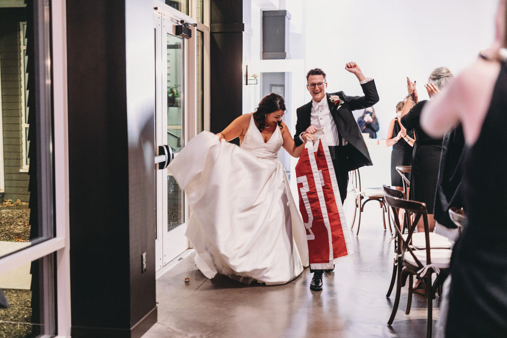 bride and groom enter wedding with IU flag at bluffs wedding