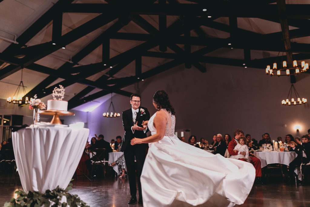 bride and groom first dance in front of wedding cake with flowing dress at bluffs wedding