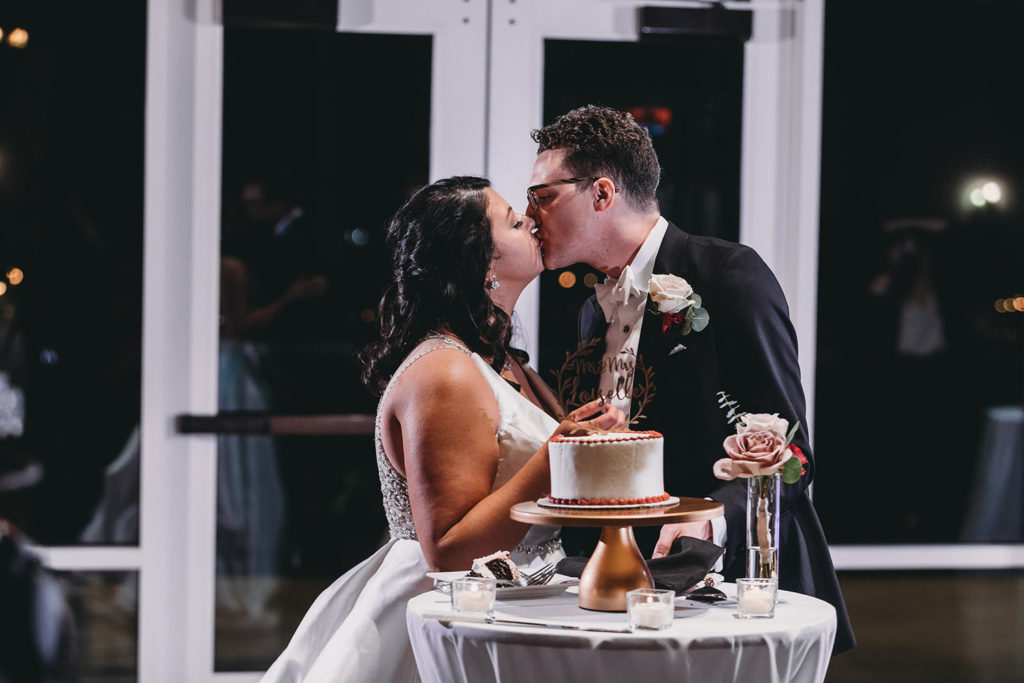 bride and groom kiss after cutting cake at bluffs wedding