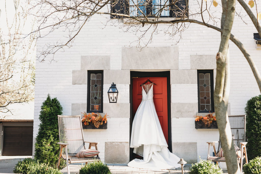 wide shot wedding dress on red door before bluffs wedding