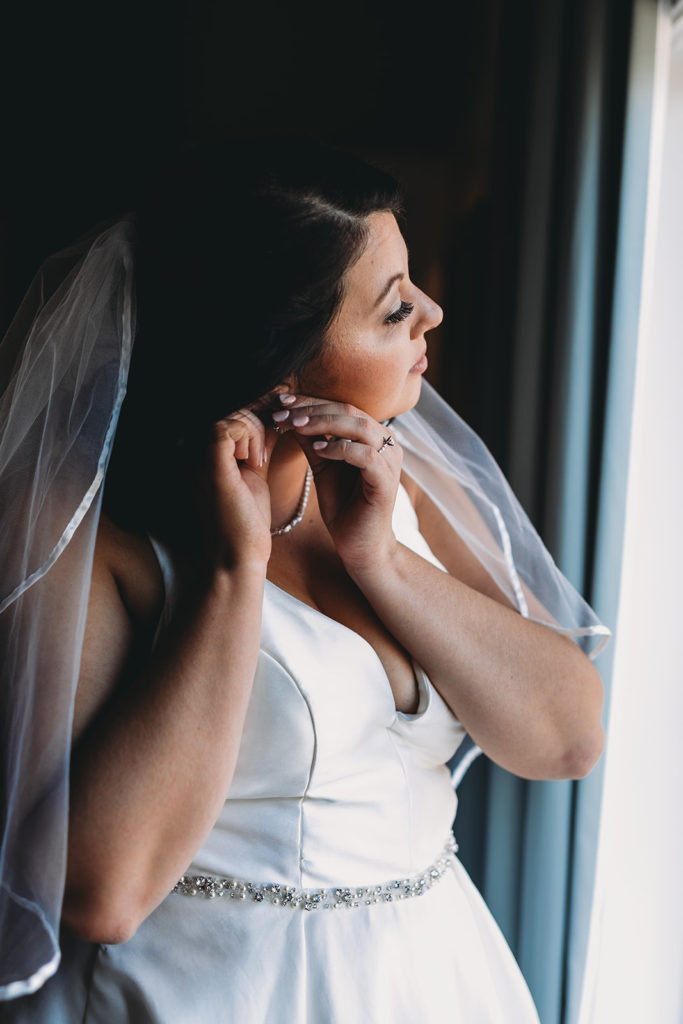 bride puts in earrings before bluffs wedding