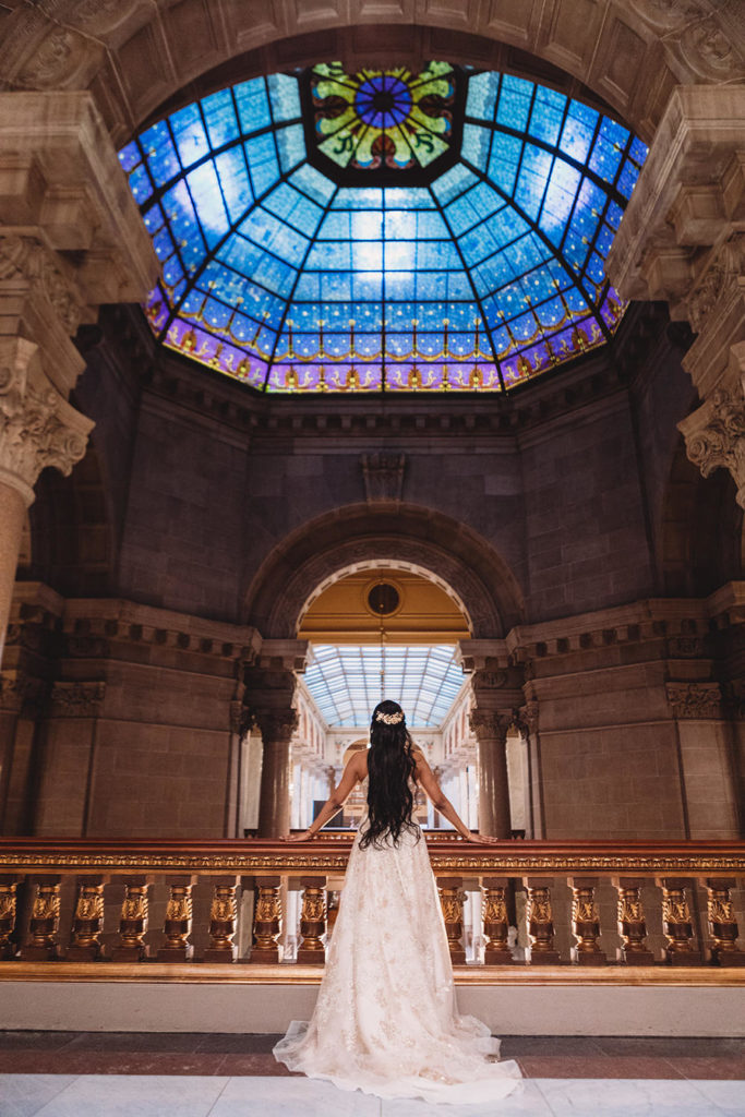 bride stands looking at stained glass during her Indiana Statehouse Elopement