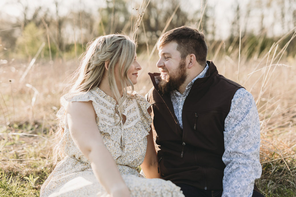 couple sitting in field in early spring during their Noblesville park engagement session