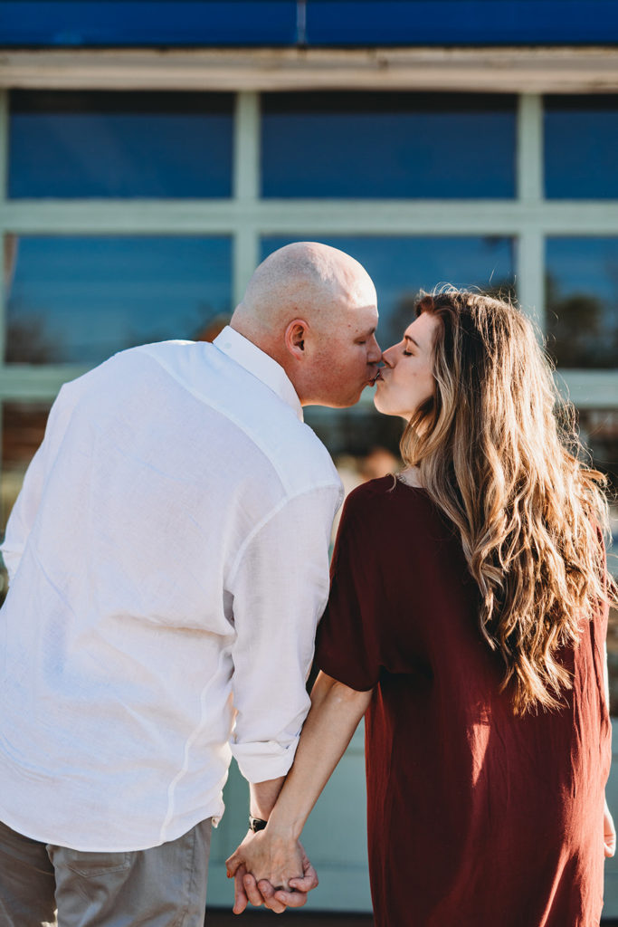 man and woman kiss in front of glass during their Fountain Square Engagement Photos