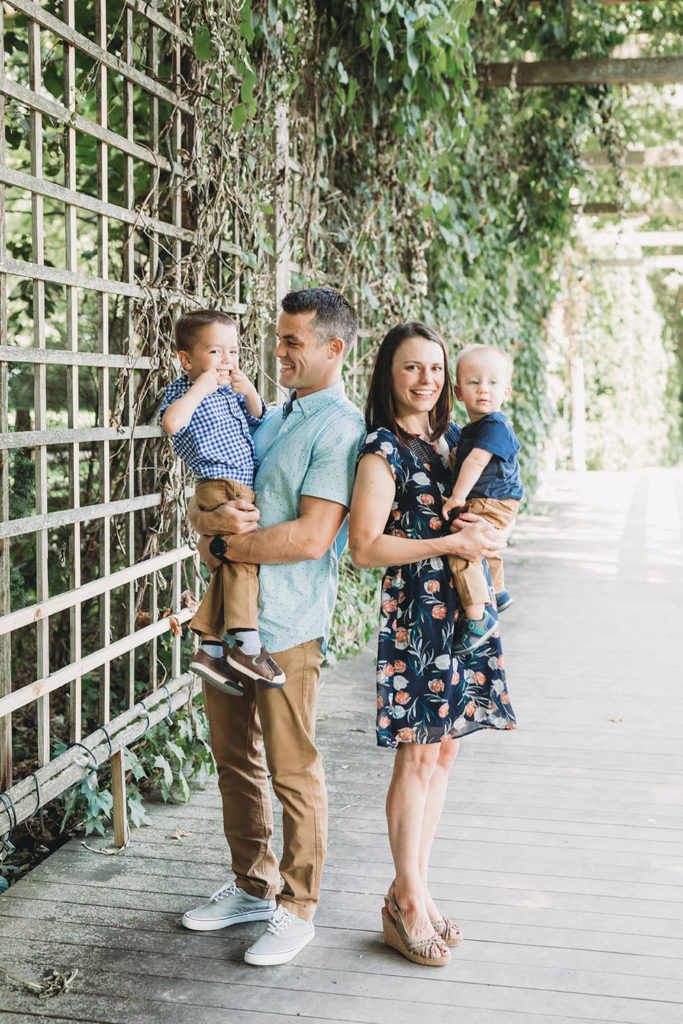 mom and dad with two toddler sons under trellis with ivy at indianapolis art center ARTSPARK for broad ripple family photos