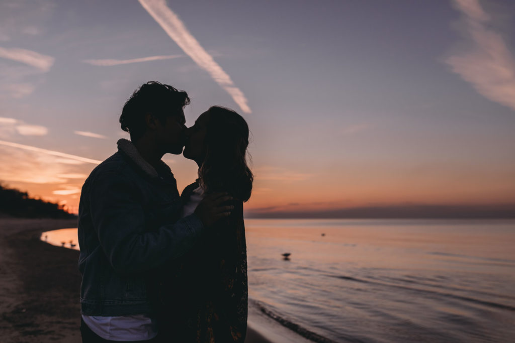 silhouette of young couple kissing at lake michigan lakeshore
