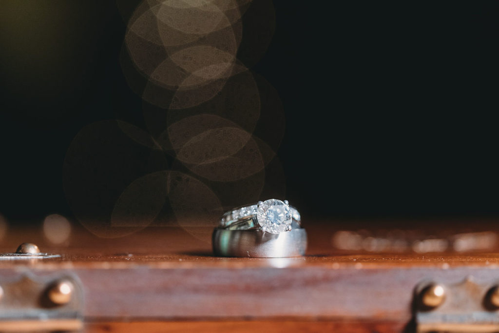 engagement ring and wedding bands with bokeh behind them during a traders point creamery elopement