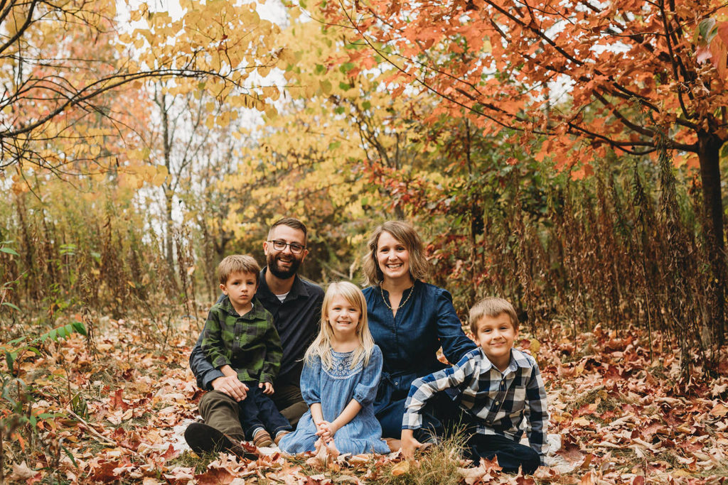 family of five sitting in leaves captured by a Carmel Family Photographer