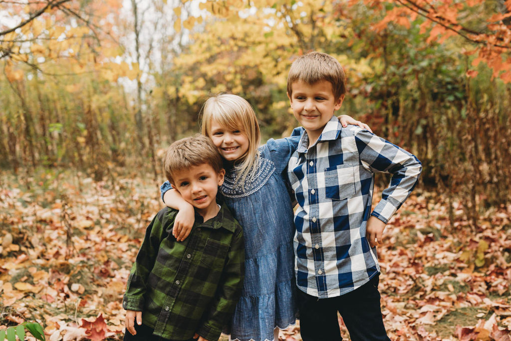 three kids in autumn captured by a Carmel Family Photographer