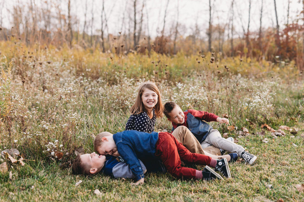 toddler tackles brother while other siblings laugh in these Carmel Fall Family Photos