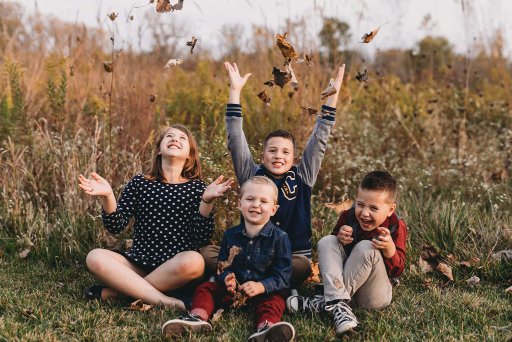 four kids throw leaves in air in these Carmel Fall Family Photos