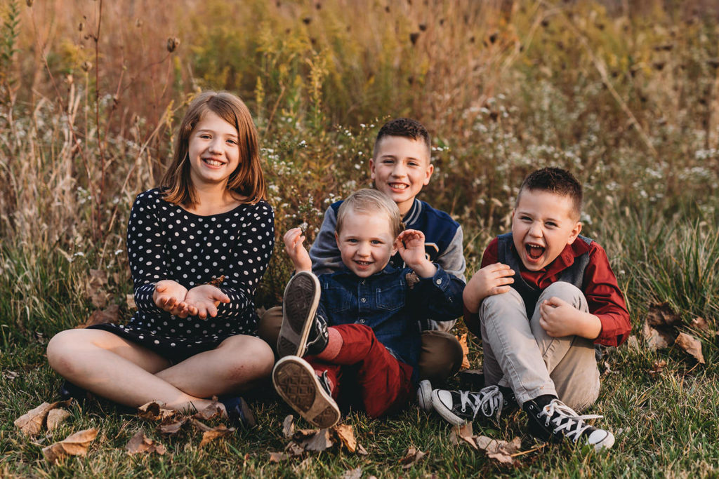 leaves fall while kids laugh in these Carmel Fall Family Photos