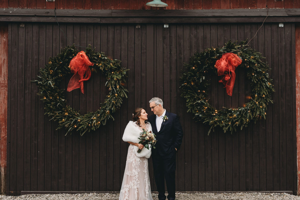 bride and groom look lovingly at each other in front of wreaths during their traders point creamery elopement