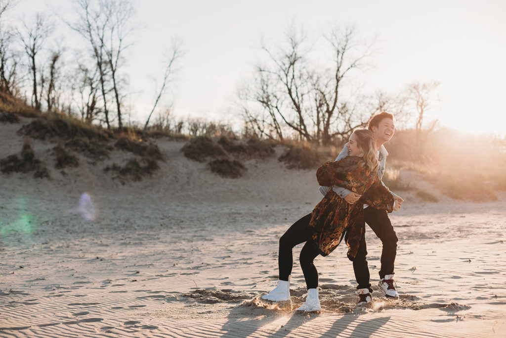 young man and young woman dance and fall on the beach at the beach in Indiana at Lake Michigan