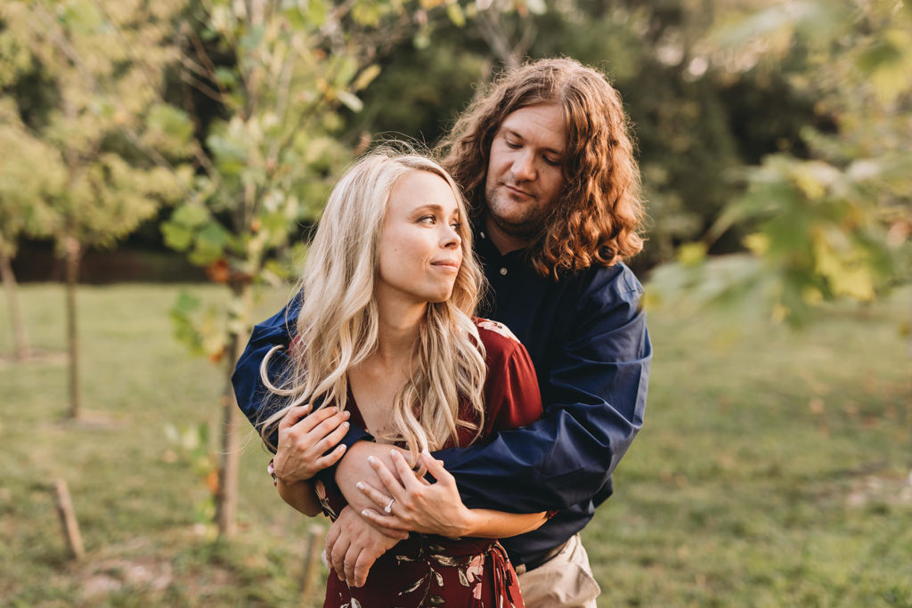 man with long hair hugs blonde woman in downtown muncie engagement session
