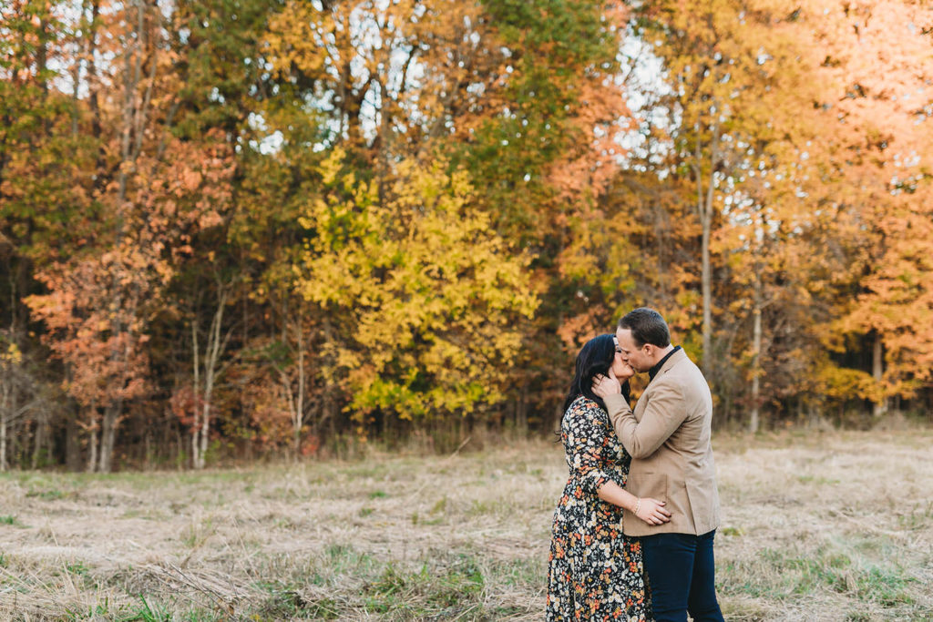 couple kiss in front of orange and yellow trees during their starkey park engagement photos