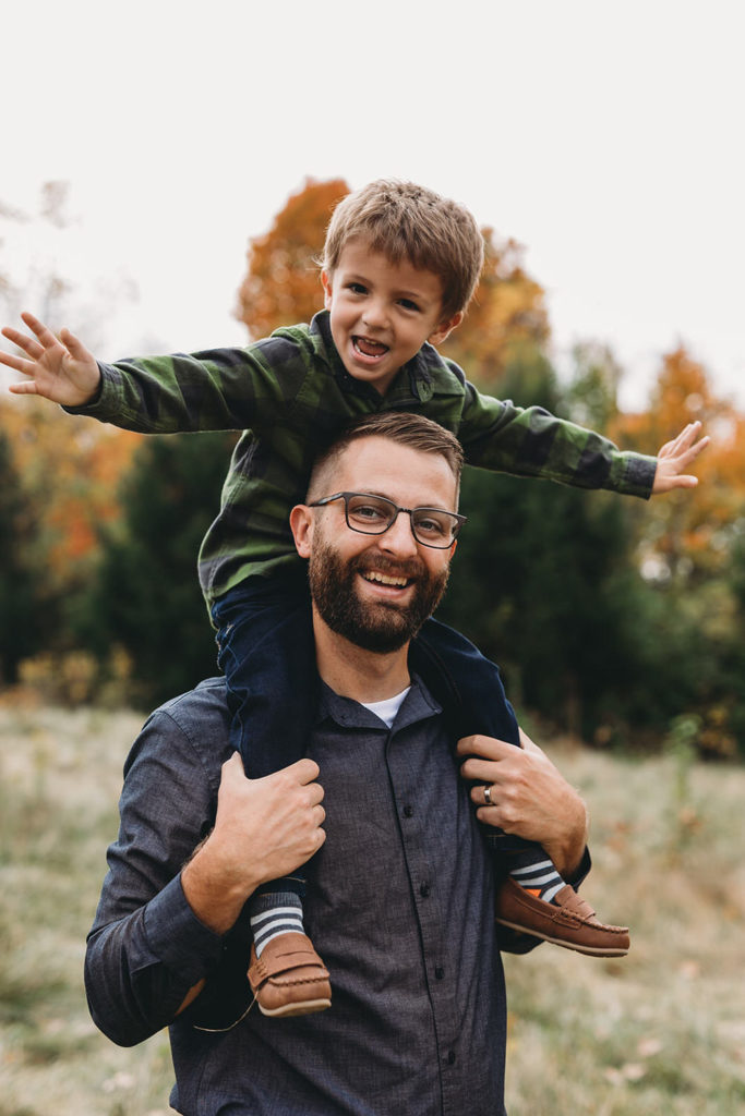 son on his dad's shoulders smiling captured by a Carmel Family Photographer