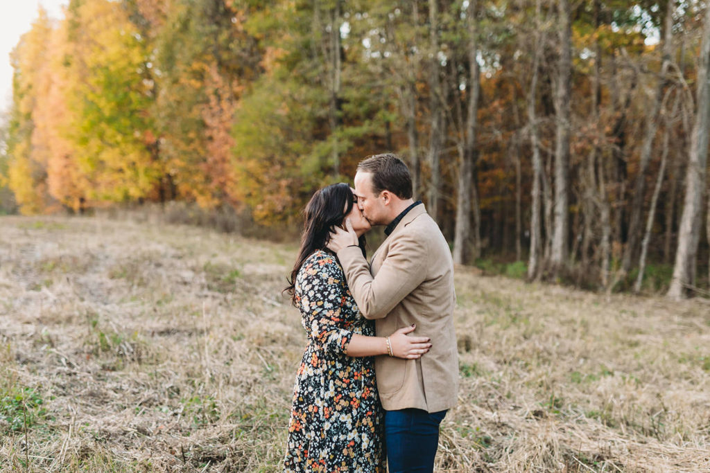 couple kiss in field in autumn during their starkey park engagement photos