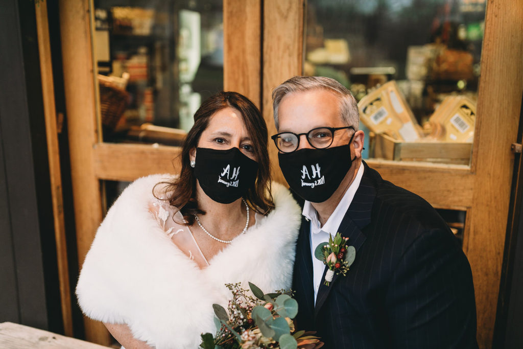 masked bride and groom  in front of a rust building during their traders point creamery elopement
