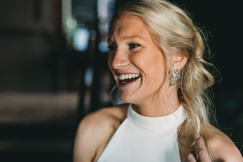 blonde bride laughing in window light during their indy canal wedding