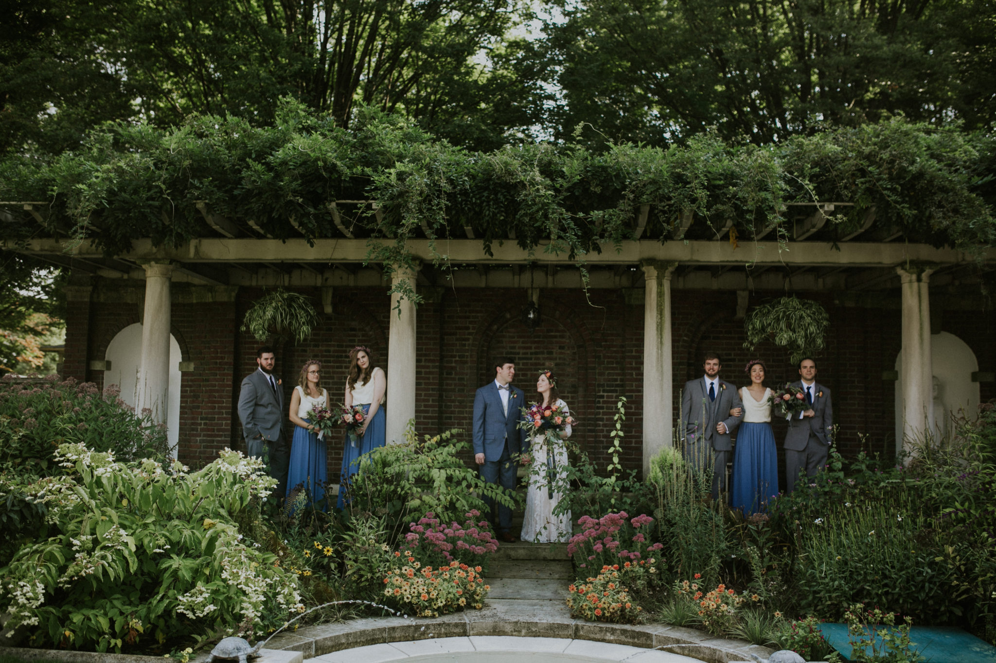 a bride and groom stand amongst lush greenery at the inn at irwin gardens