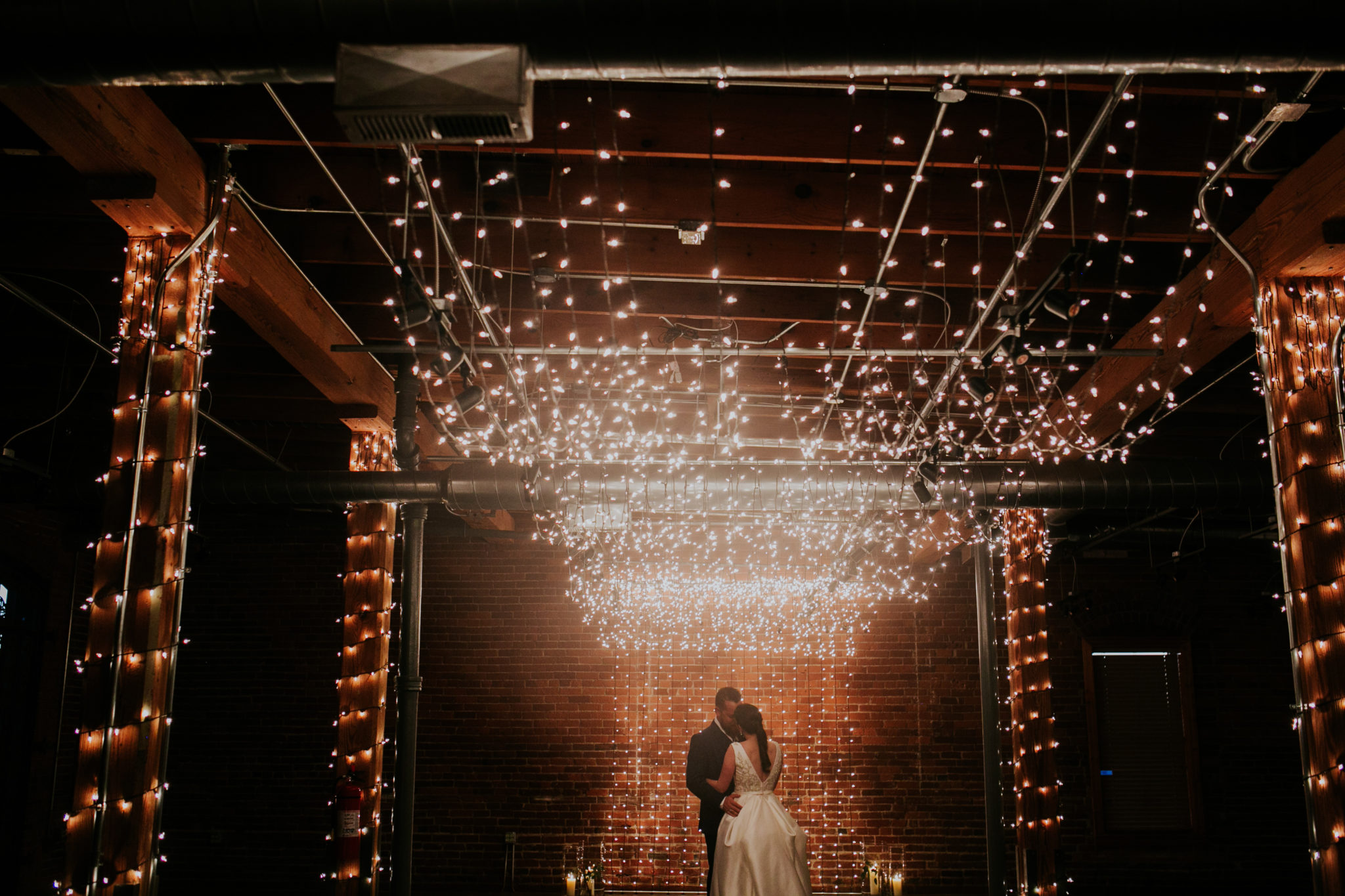 a bride and groom dance in a dark room filled with fairy lights at mill top in noblesville indiana on their wedding day