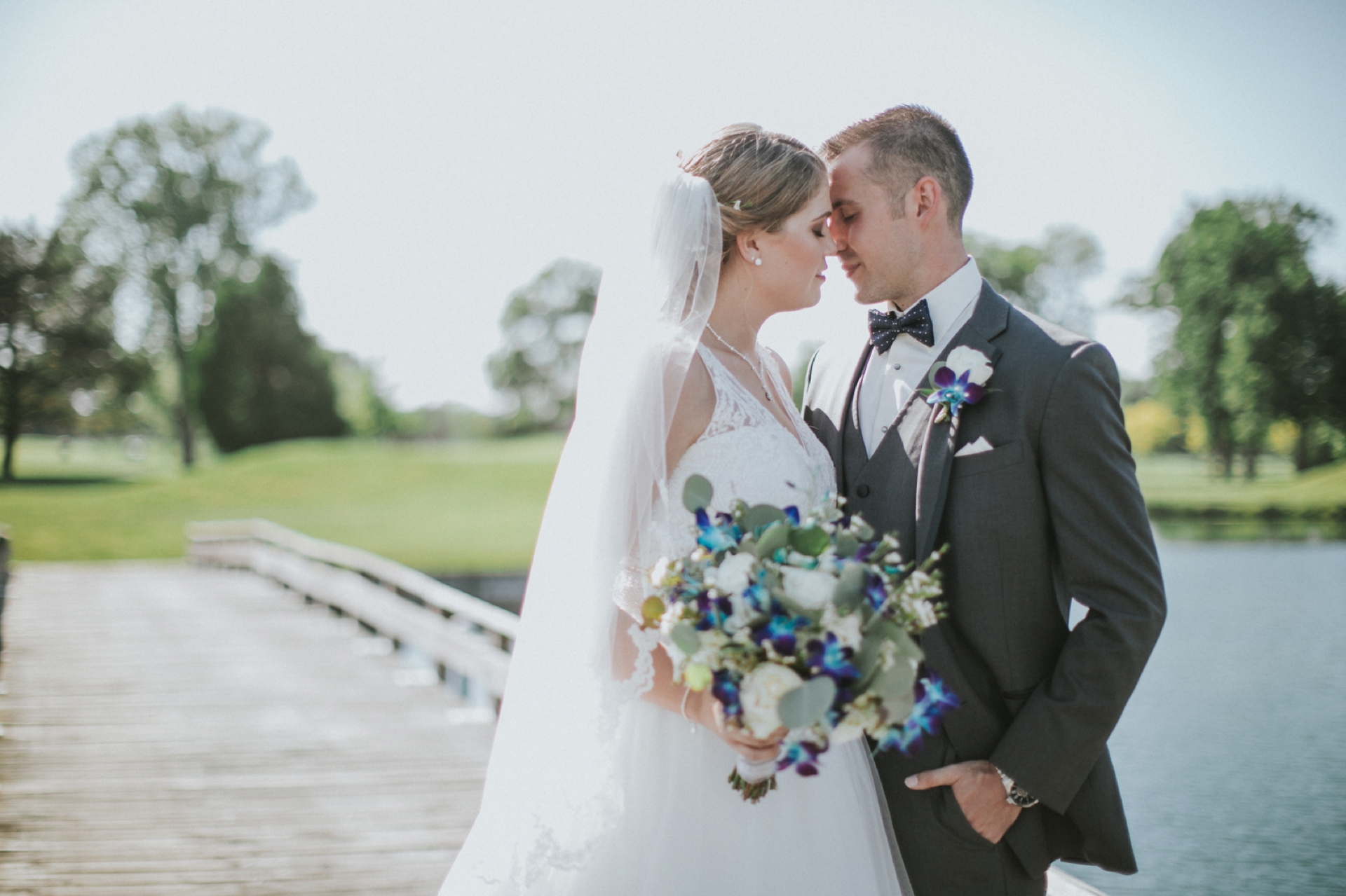 Bride and Groom standing on a bridge at Swan Lake Golf Course in Plymouth Indiana with their foreheads touching