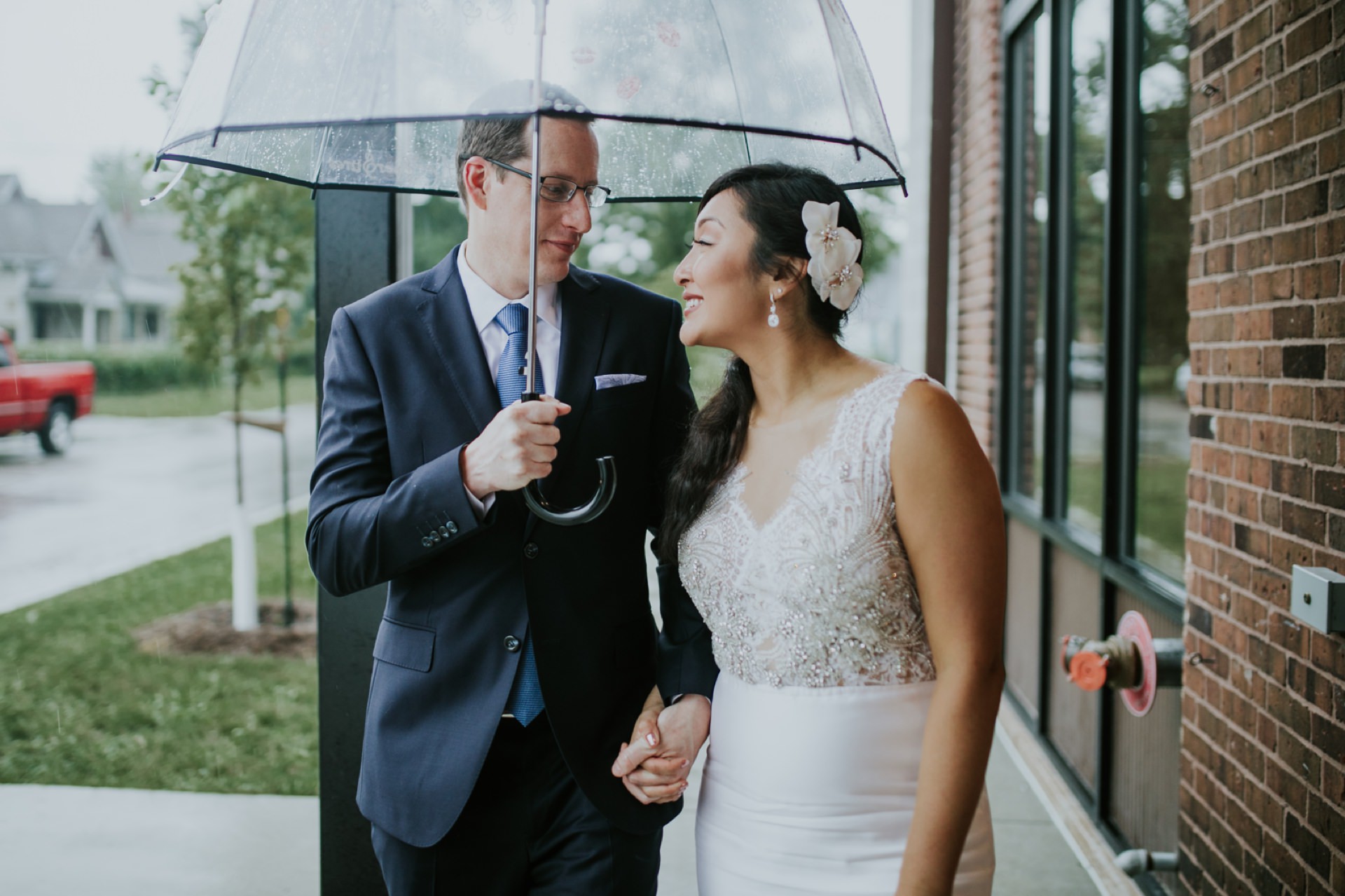 bride and groom under umbrella backlit by warm light on a rainy Neidhammer wedding day