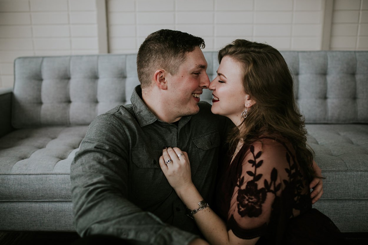 man and woman kissing inside industrial building with neo-modern furniture during Louisville engagement session