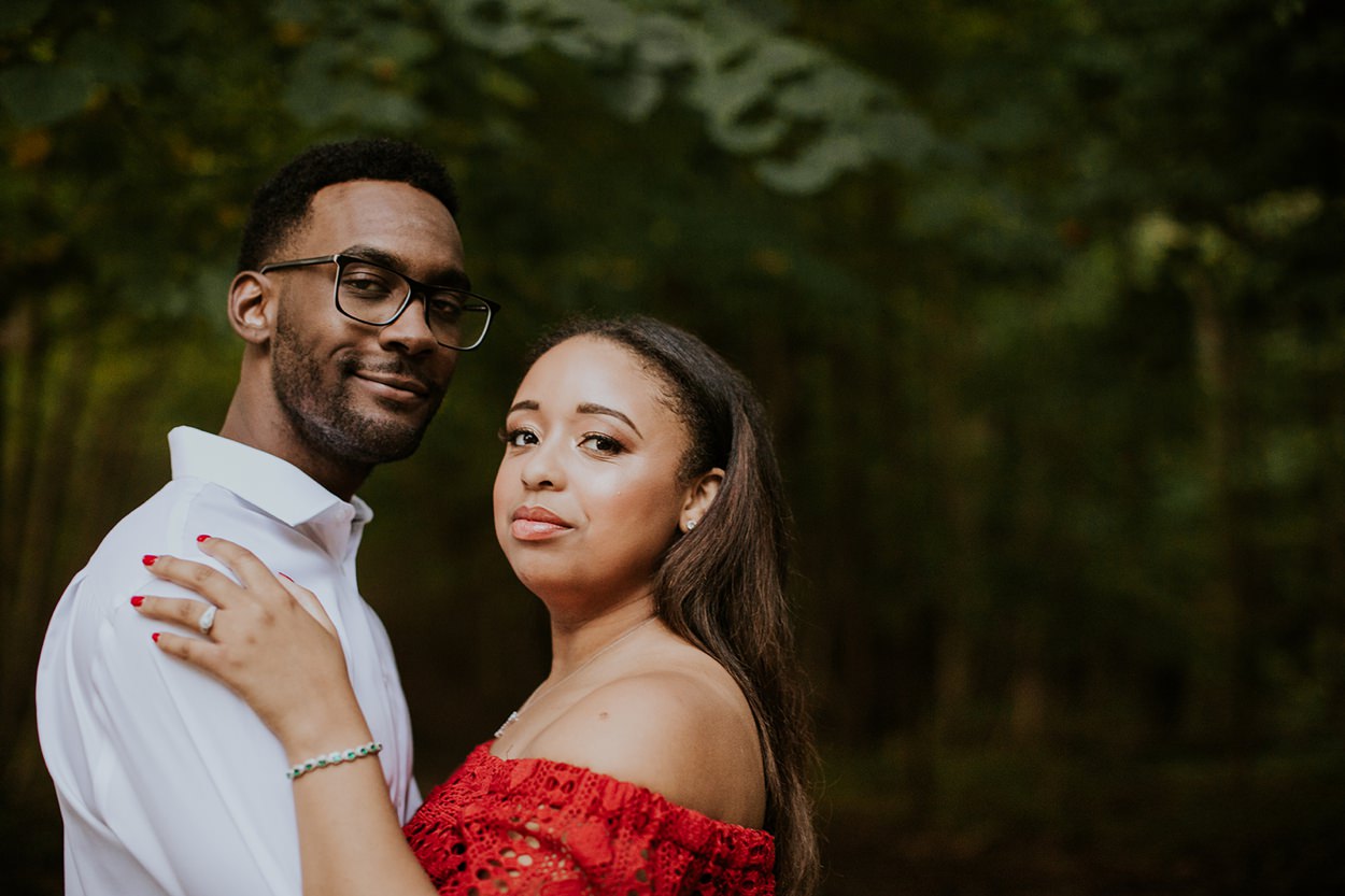 a man with glasses hugs a woman in a red shirt at this eagle creek engagement photography session