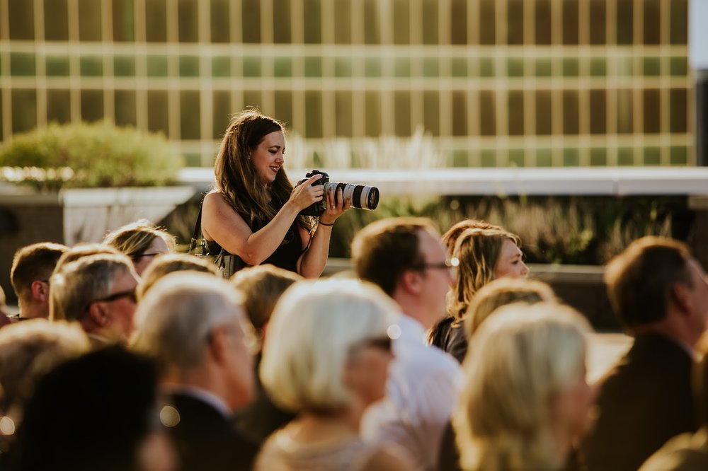 woman shooting a wedding in golden light in sea of wedding guests used promotionally for her podcast spot filling in for her wedding hungover husband on the wedding photo hangover podcast