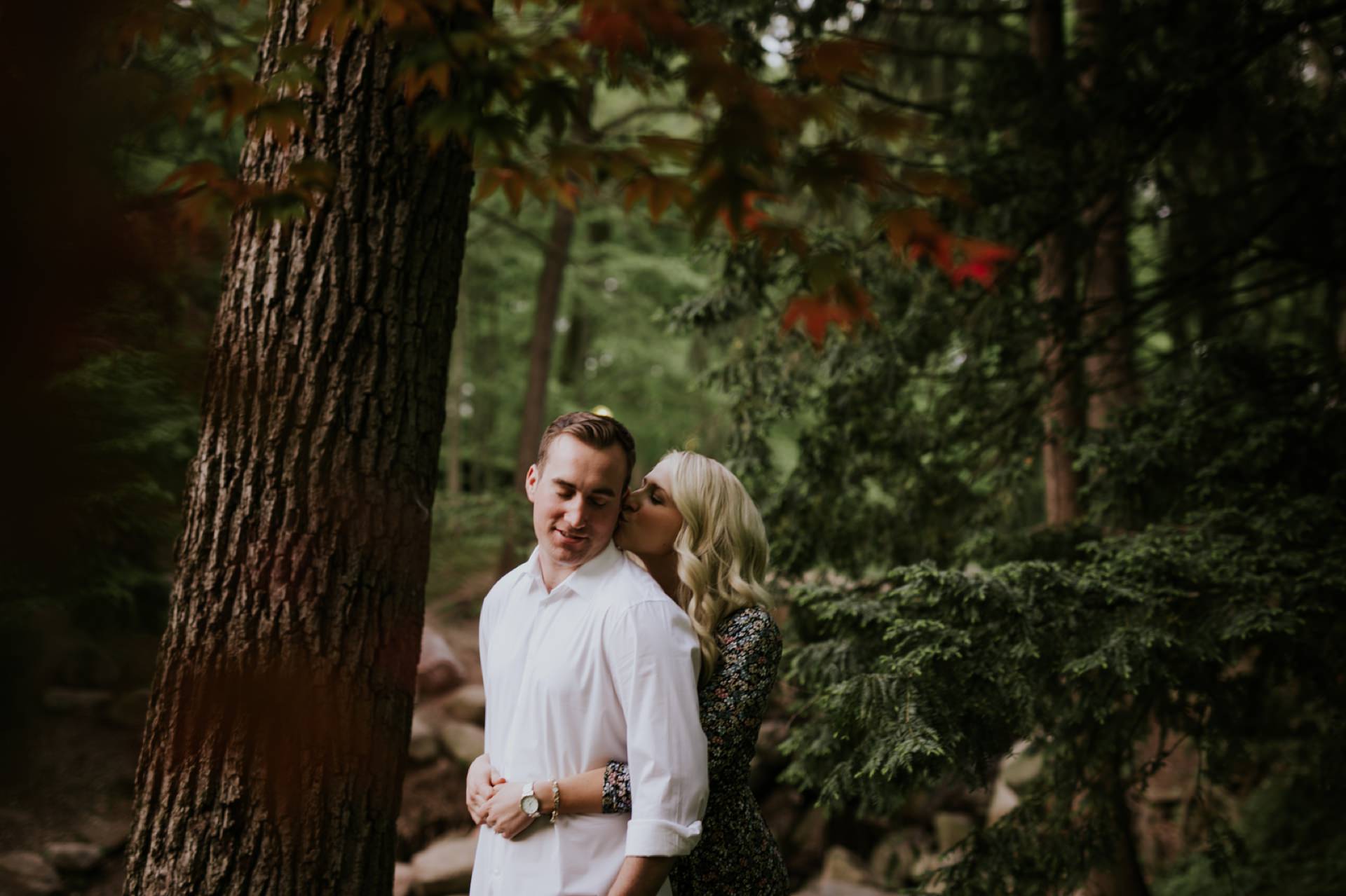 in the woods at this holcomb gardens engagements photos session a blonde woman kisses a brown haired man