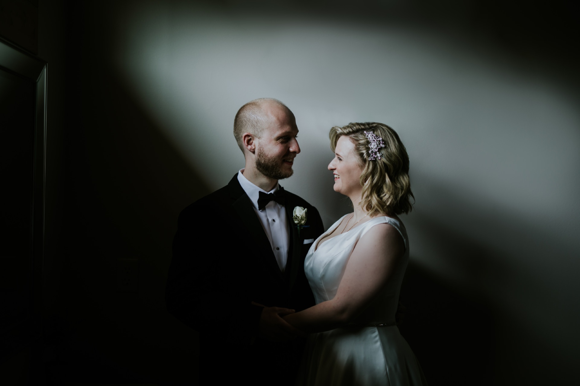 bride and groom in dark and moody window light at their willow lake wedding