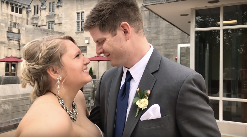 bride and groom smiling at each other in front of stone building