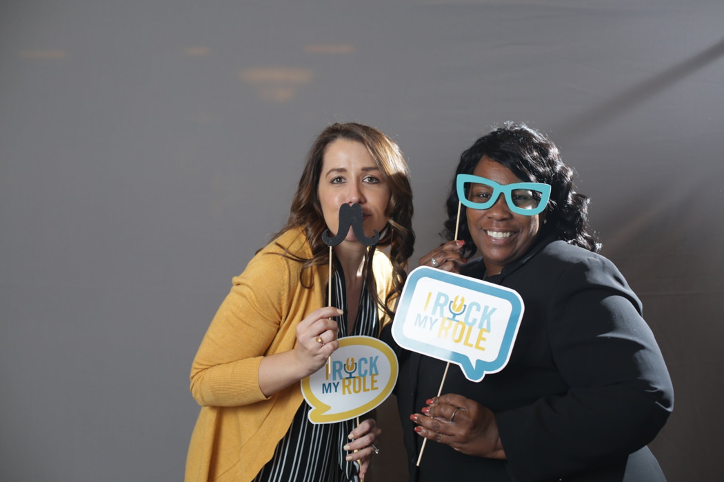 woman with a fake mustache and a woman with fake glasses smile at an Indy Corporate Photobooth event