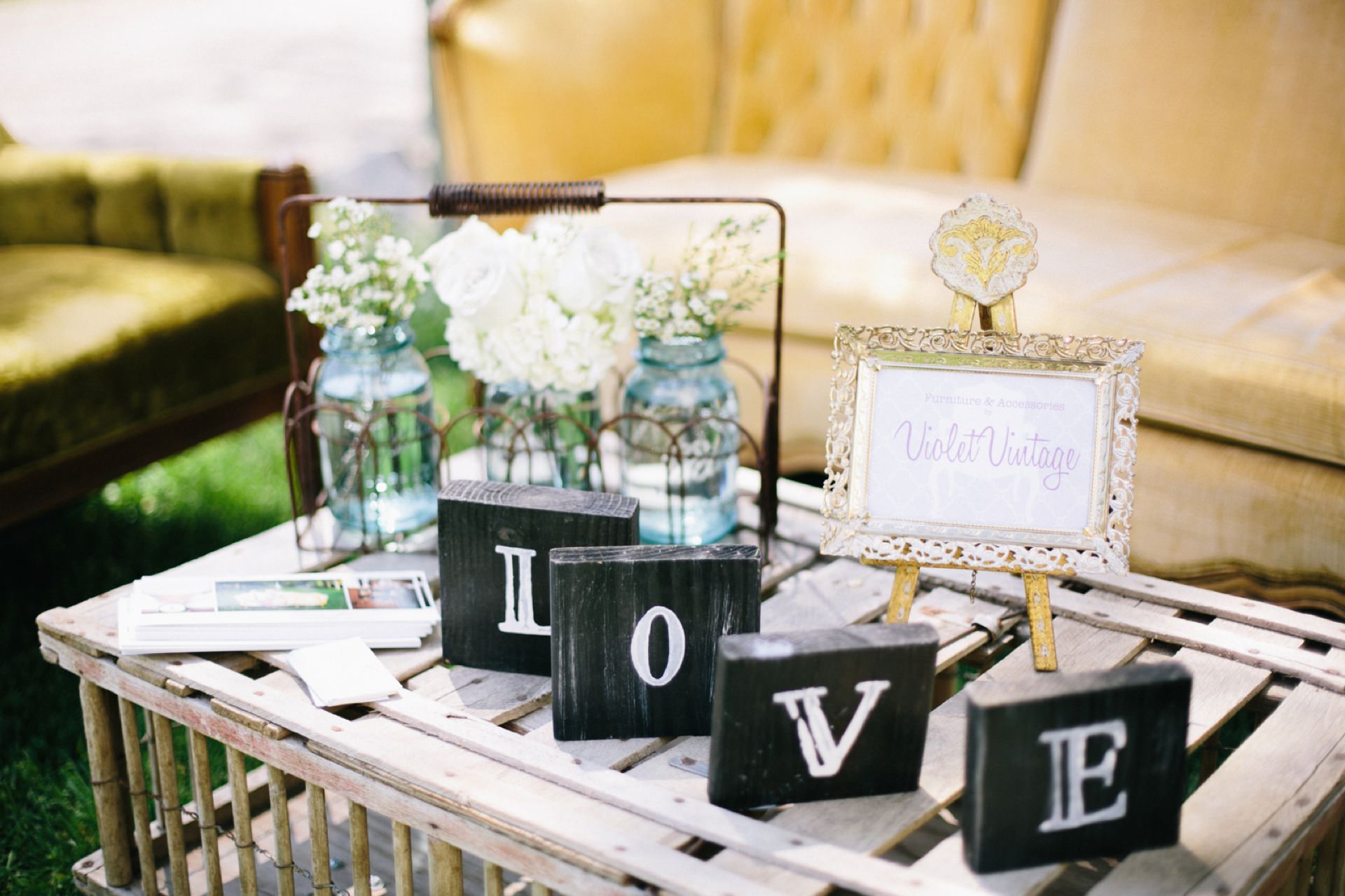 the word love spelled out in white letters on four wooden blocks in front of a couch at the prairie guest house bridal show