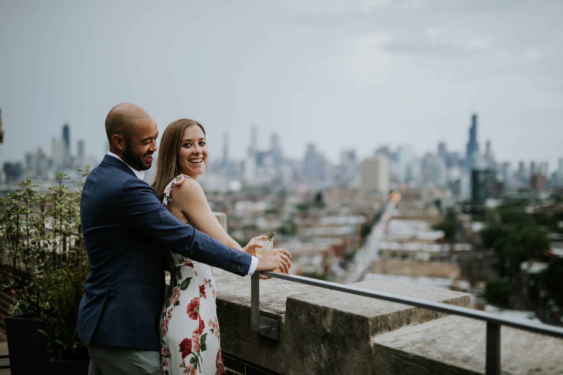 a man in a suit and a woman in a dress in their robey engagement photos with the chicago skyline behind them
