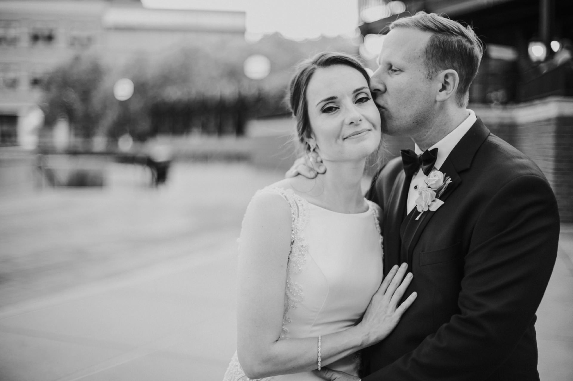 black and white photo of groom kissing bride on head during the cocktail hour of their canal 337 wedding