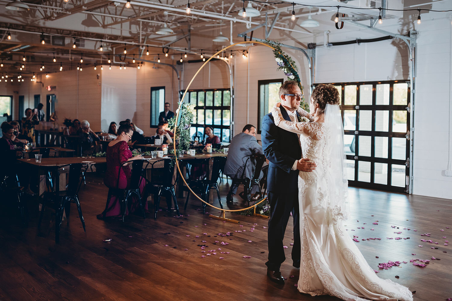bride and groom dance in front of wooden circle and guests at a Bash wedding