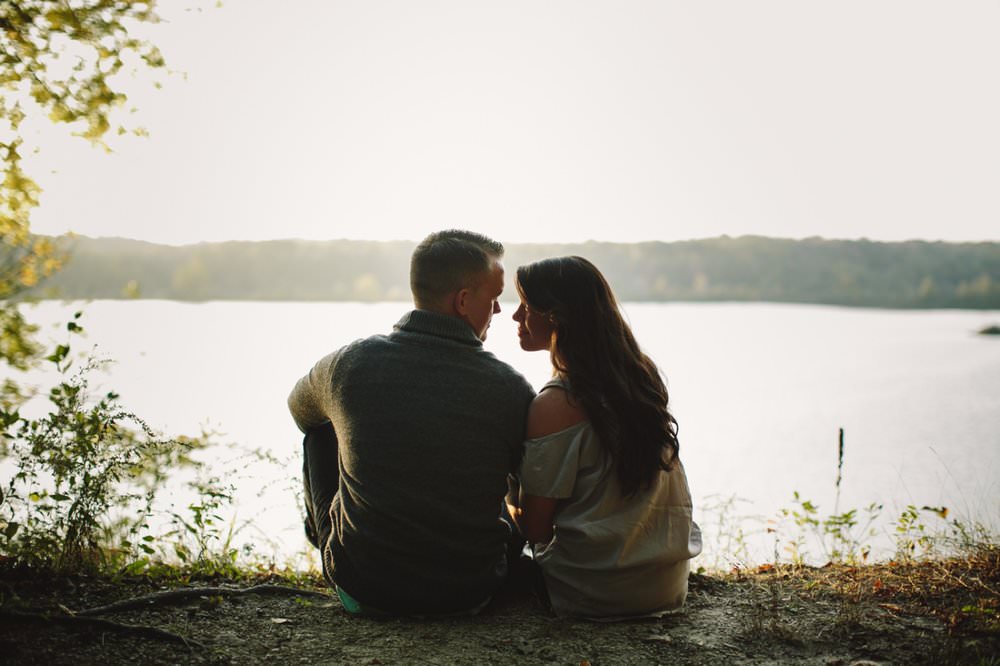 man and woman sit in front of eagle creek reservoir, one of the Best Indianapolis Engagement Photo Locations