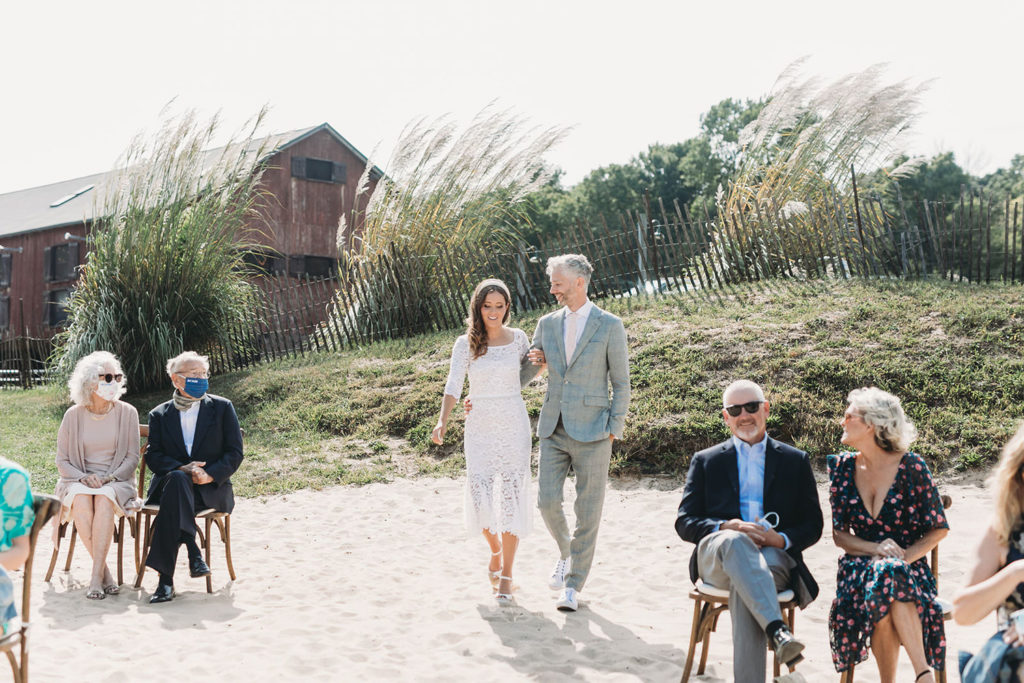 bride and groom walk down aisle together on beach for their wedding ceremony during their traders point creamery wedding which is one of the Best Indianapolis Barn Venues