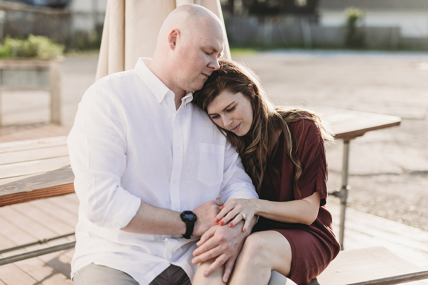 couple sits at table and cuddles at sunset during their Fountain Square Engagement Photos