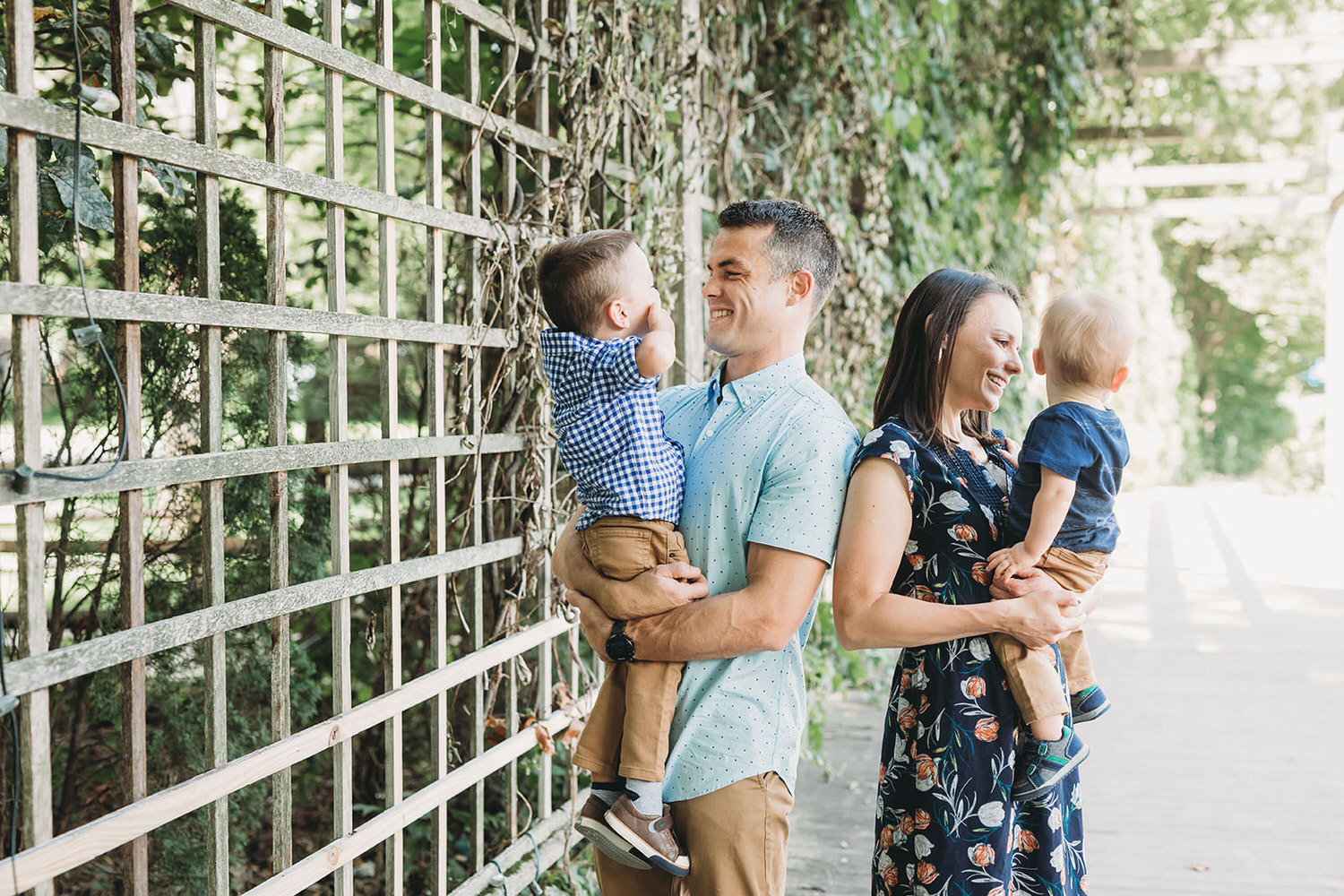 parents smile at kids under ivy covered trellis at indianapolis art center ARTSPARK for broad ripple family photos