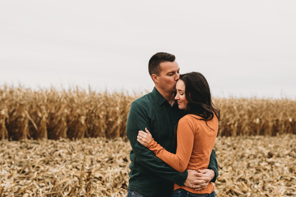 man in green shirt hugs wife in orange sweater during this Central Indiana Family Photography session