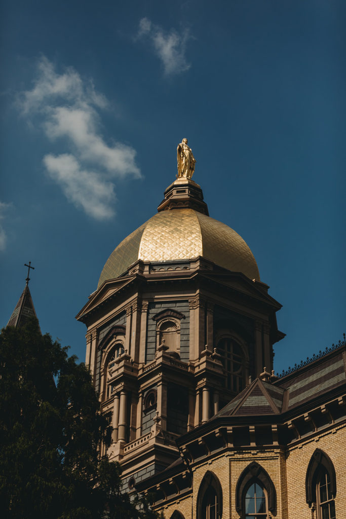 The Golden Dome at the University of Notre Dame on a cloudy day with a deep blue sky